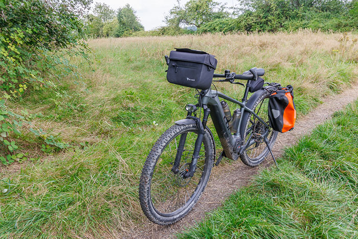 Die Lenkertasche ist von MiVelo, wasserdicht, mit abnehmbaren Handyfach. Bei einem unfreiwilligen Test auf einem groben Singetrail l&ouml;sten sich die Magnete des Handyfachs mehrmals. Also nur f&uuml;r normale Touren geeignet, nicht f&uuml;r grobe Trails ;-). Meiner Meinung nach kann man auf dem Handy-Display im Fach auch nicht mehr viel erkennen, deshalb k&ouml;nnte man es sich auch sparen.